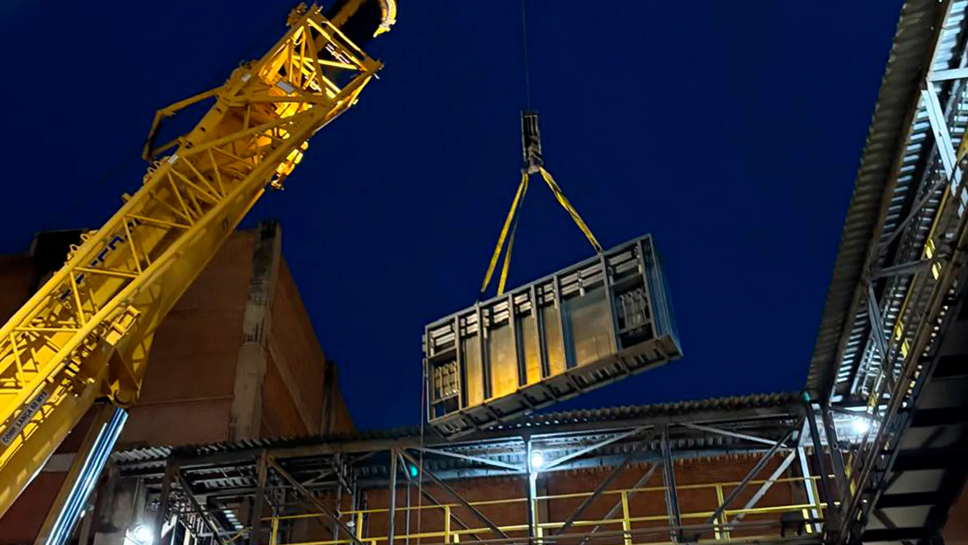 Içamento noturno de painel elétrico com guindaste em obra industrial da PSO